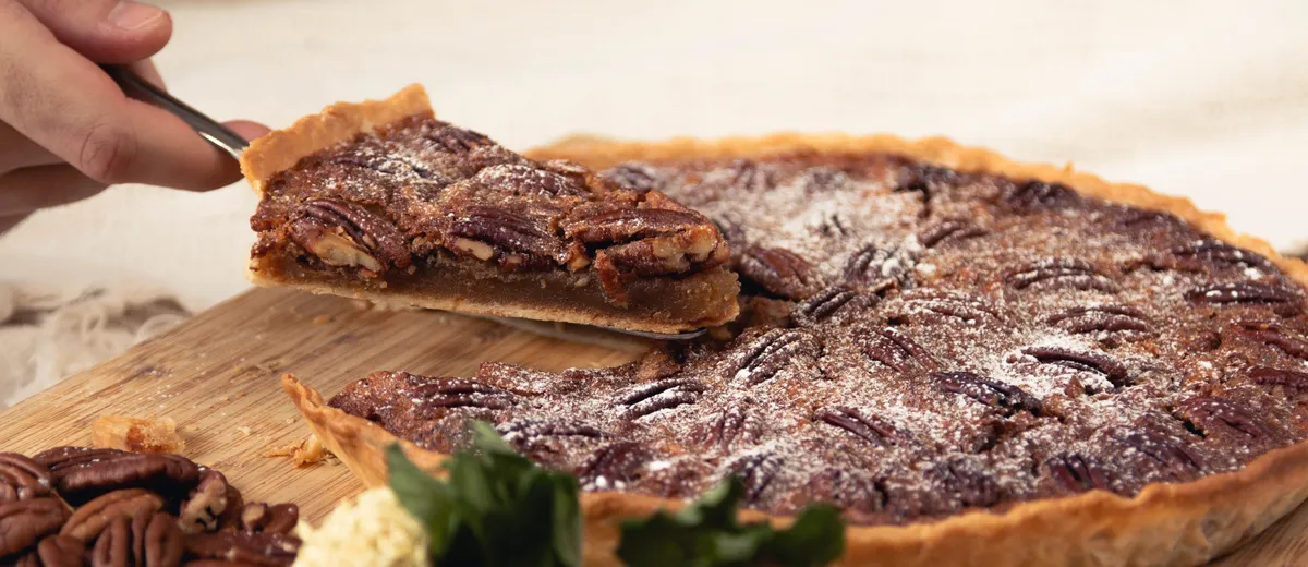 Pecan pie dorée aux noix de pécan caramélisées, une part coupée révélant l'appareil ambré et fondant