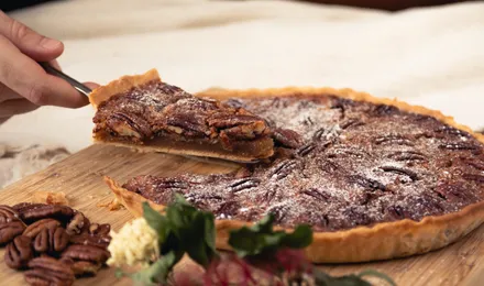 Pecan pie dorée aux noix de pécan caramélisées, une part coupée révélant l'appareil ambré et fondant
