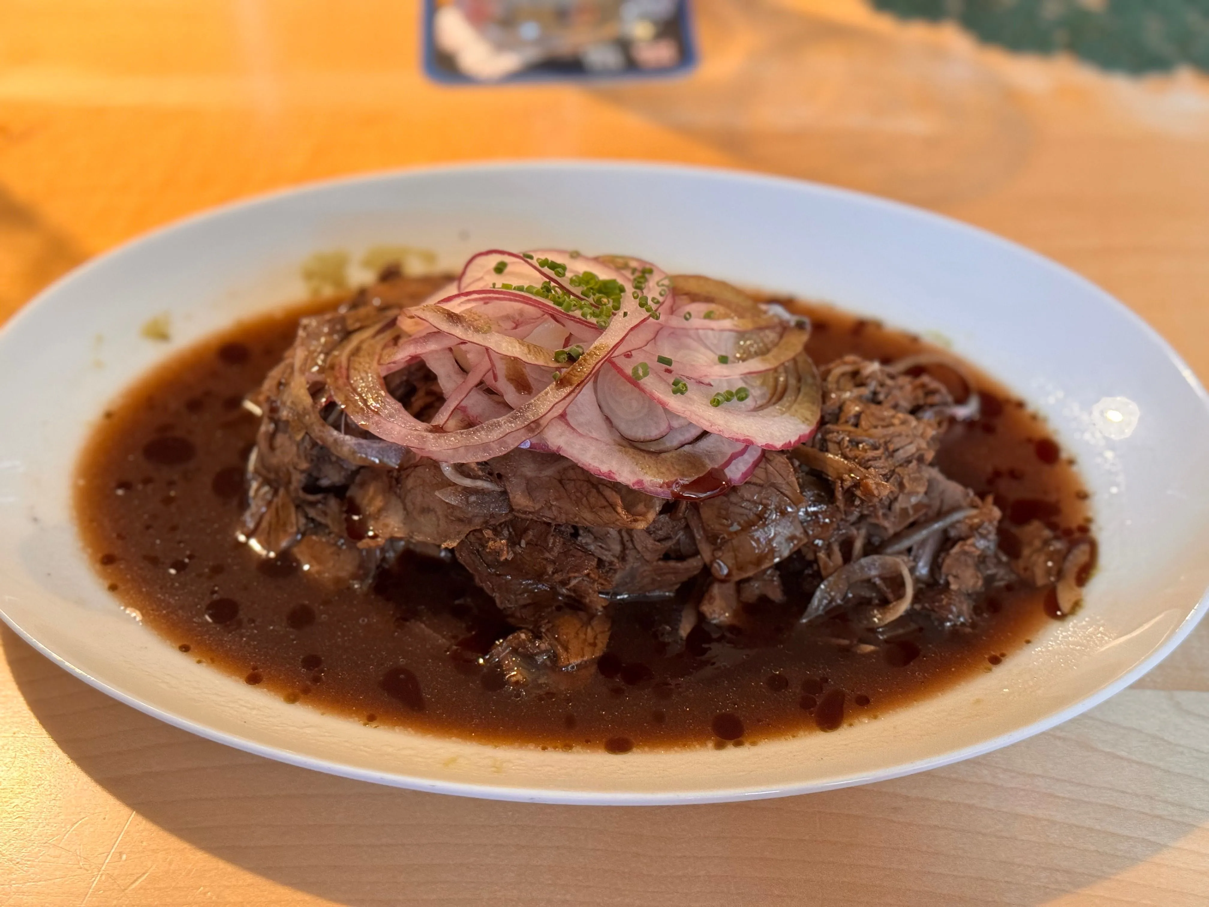 Sauerbraten braisé nappé de sauce brune, servi avec knödel et chou rouge