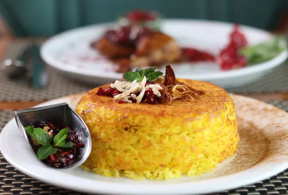 Riz persan safrané démoulé sur une assiette, révélant une croûte de tahdig dorée et croustillante