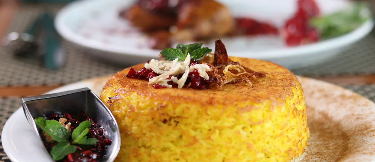 Riz persan safrané démoulé sur une assiette, révélant une croûte de tahdig dorée et croustillante