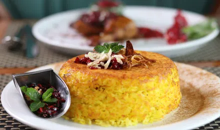 Riz persan safrané démoulé sur une assiette, révélant une croûte de tahdig dorée et croustillante