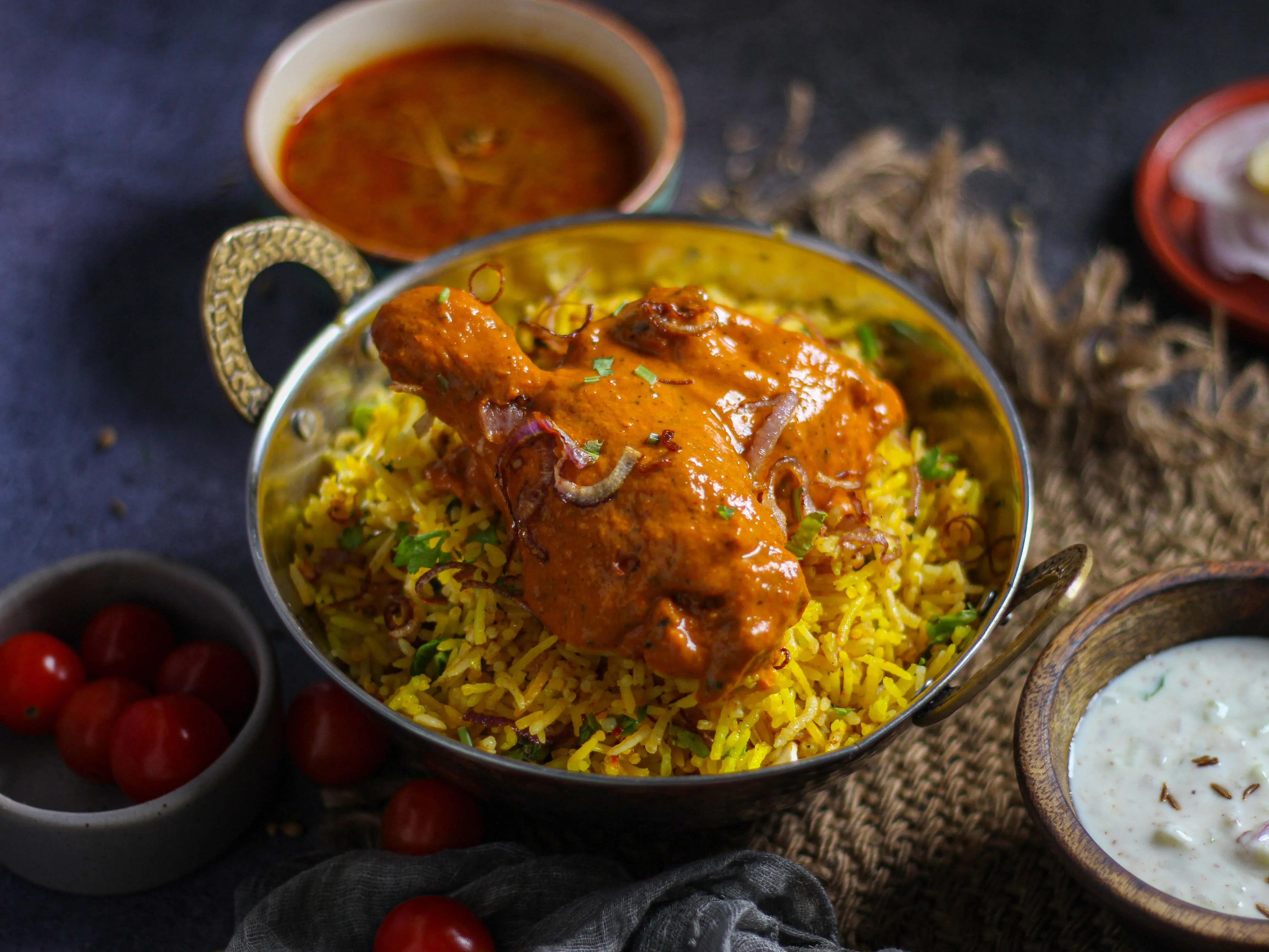 Biryani de poulet fumant dans une marmite, riz basmati safrané parsemé d'oignons frits et de coriandre