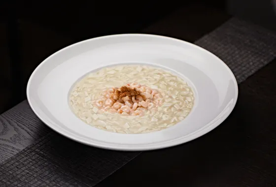 Assiette creuse de risotto crémeux à la parmigiana, onctueux et brillant, parsemé de parmesan