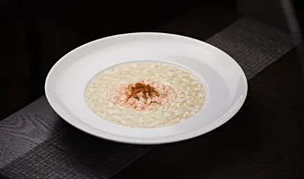 Assiette creuse de risotto crémeux à la parmigiana, onctueux et brillant, parsemé de parmesan