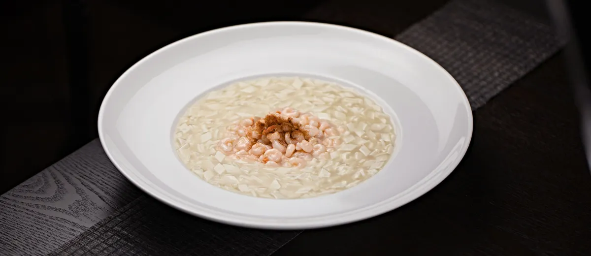 Assiette creuse de risotto crémeux à la parmigiana, onctueux et brillant, parsemé de parmesan