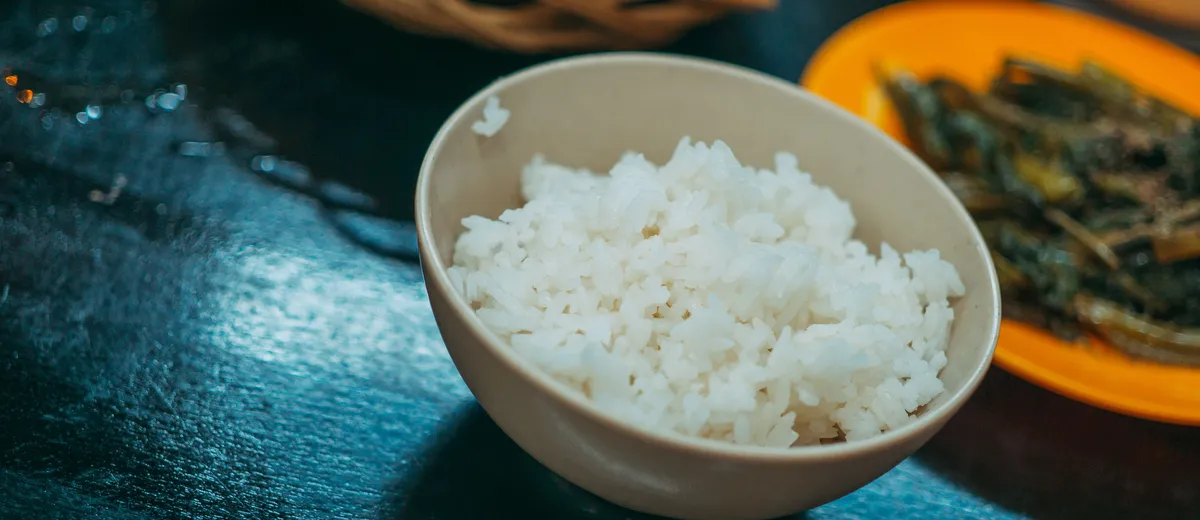 Riz vinaigré japonais brillant et collant dressé dans un bol en bois, prêt pour la préparation de sushis