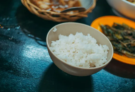 Riz vinaigré japonais brillant et collant dressé dans un bol en bois, prêt pour la préparation de sushis