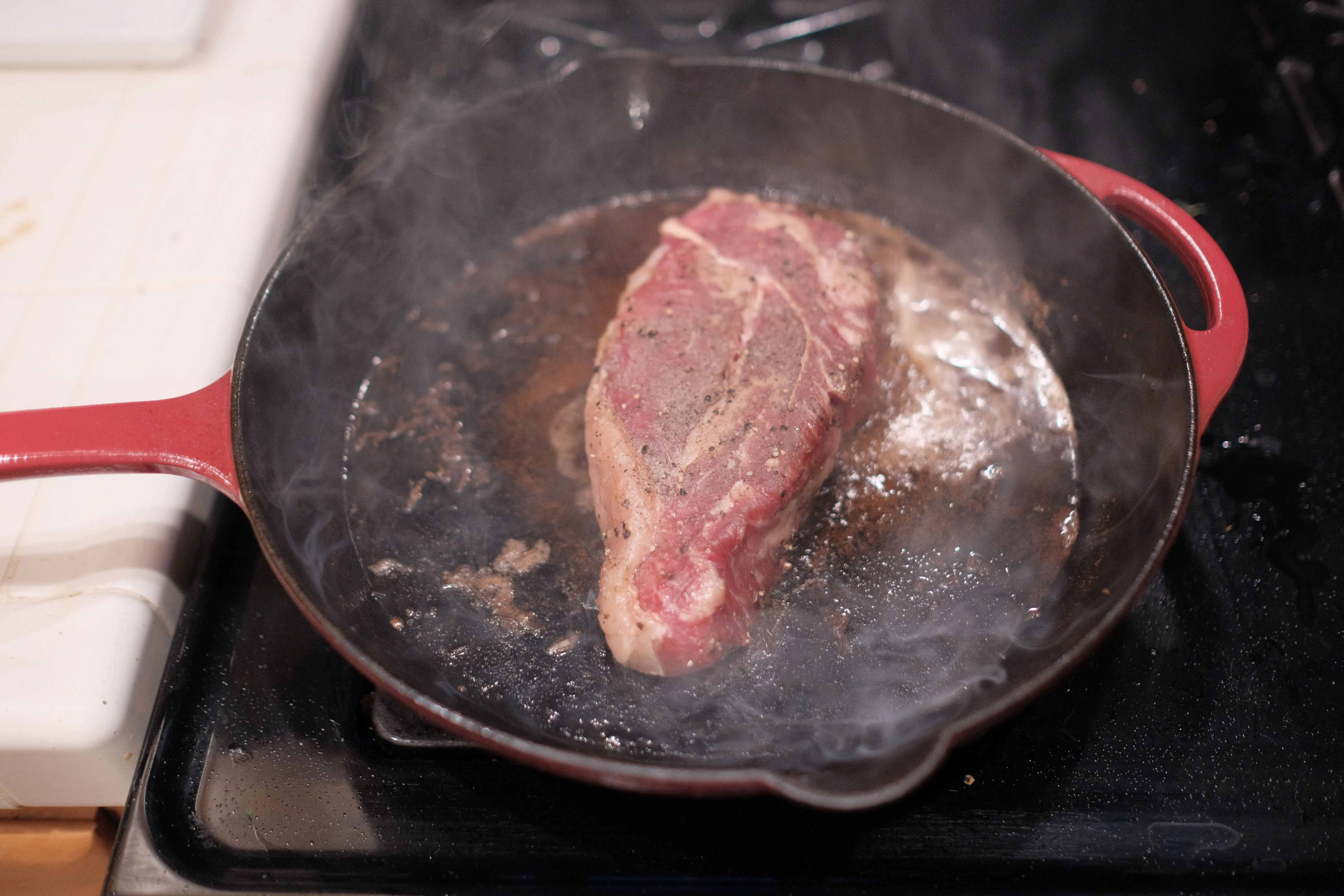 Pièce de bœuf en train d'être saisie dans une poêle en fonte très chaude