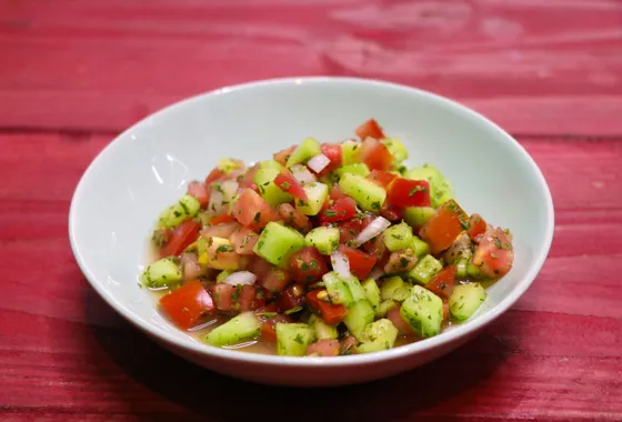 Salade Shirazi en petits dés de concombre, tomate et oignon rouge, parsemée de menthe séchée dans un bol en céramique