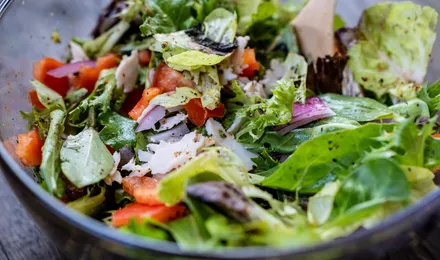 Saladier de feuilles de laitue vertes brillantes de vinaigrette avec échalote ciselée