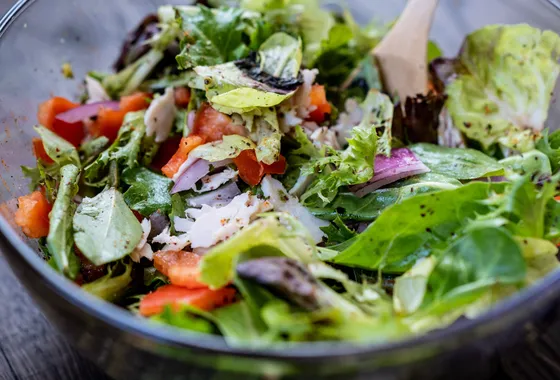 Saladier de feuilles de laitue vertes brillantes de vinaigrette avec échalote ciselée
