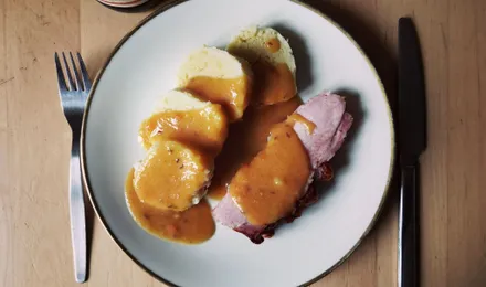Sauerbraten tranché, rôti de bœuf allemand nappé d'une sauce brune brillante, accompagné de chou rouge et de knödel.