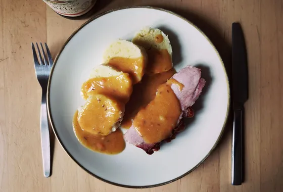 Sauerbraten tranché, rôti de bœuf allemand nappé d'une sauce brune brillante, accompagné de chou rouge et de knödel.