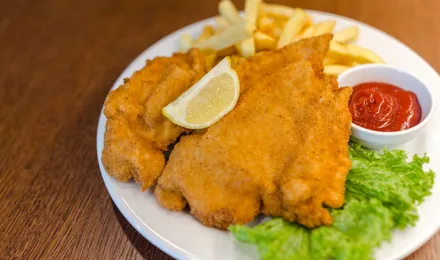 Schnitzel de porc pané et doré, servi avec un quartier de citron et des pommes de terre au persil
