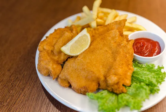 Schnitzel de porc pané et doré, servi avec un quartier de citron et des pommes de terre au persil