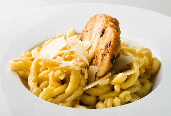 Spätzle maison dorés au beurre dans une poêle, parsemés de persil