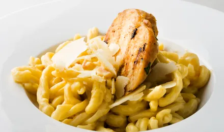 Spätzle maison dorés au beurre dans une poêle, parsemés de persil