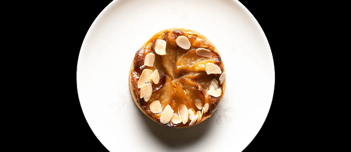 Tarte Tatin aux pommes caramélisées démoulée, quartiers dorés et brillants de caramel sur une pâte brisée croustillante