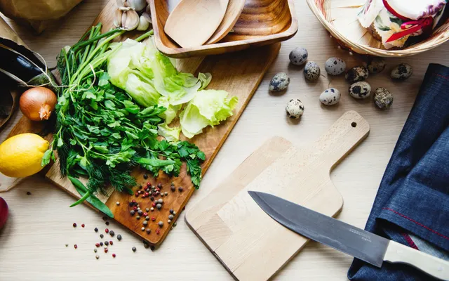 Couteau de chef, planche en bois, poêle et économe posés sur un plan de travail clair