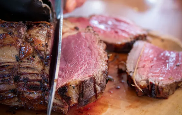 Rôti de bœuf tranché, cuisson rosée uniforme, sur une planche en bois