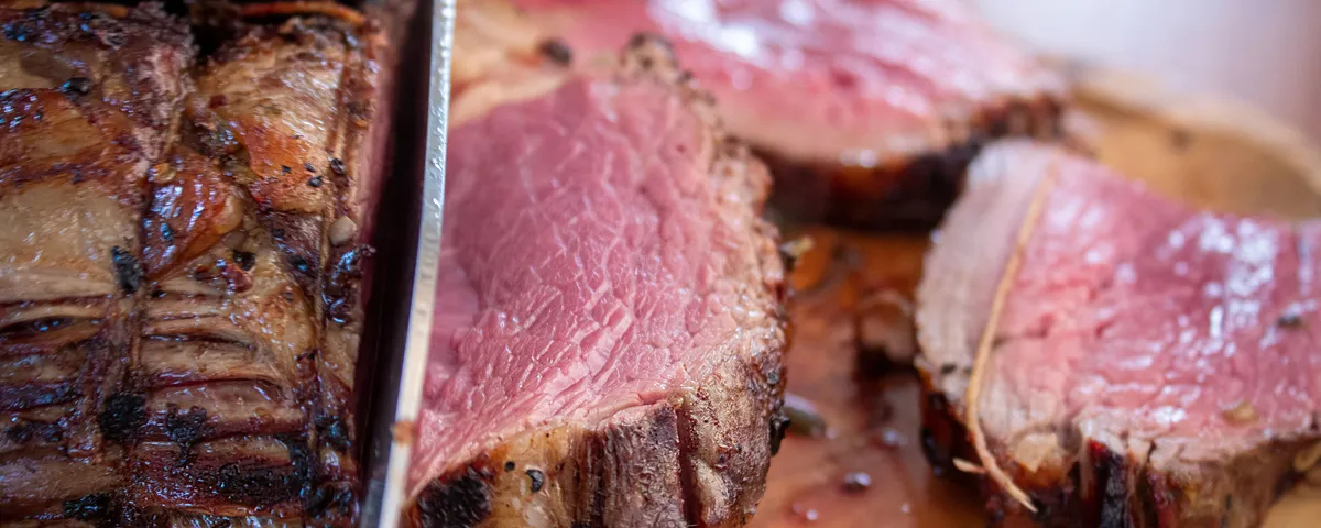 Rôti de bœuf tranché, cuisson rosée uniforme, sur une planche en bois