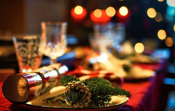 Table de fête dressée, bougies allumées et plats de Noël disposés