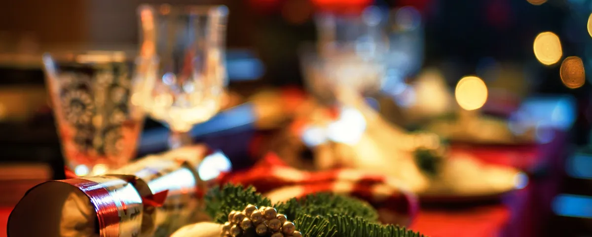 Table de fête dressée, bougies allumées et plats de Noël disposés