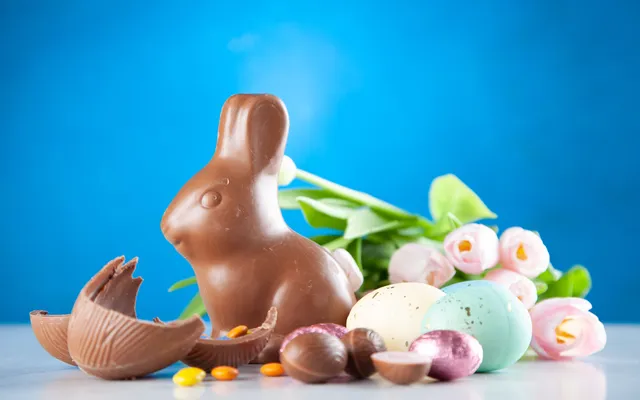 Œufs de Pâques cassés en morceaux à côté d'un bol de chocolat fondu