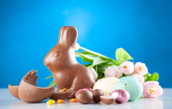Œufs de Pâques cassés en morceaux à côté d'un bol de chocolat fondu