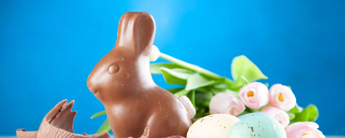 Œufs de Pâques cassés en morceaux à côté d'un bol de chocolat fondu