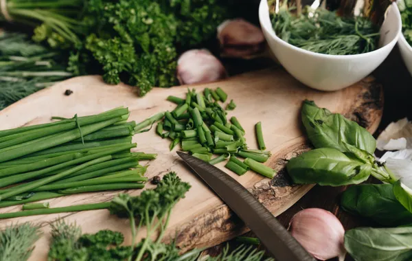 Assortiment d'herbes aromatiques fraîches en bottes — basilic, thym, persil, romarin — sur une planche en bois