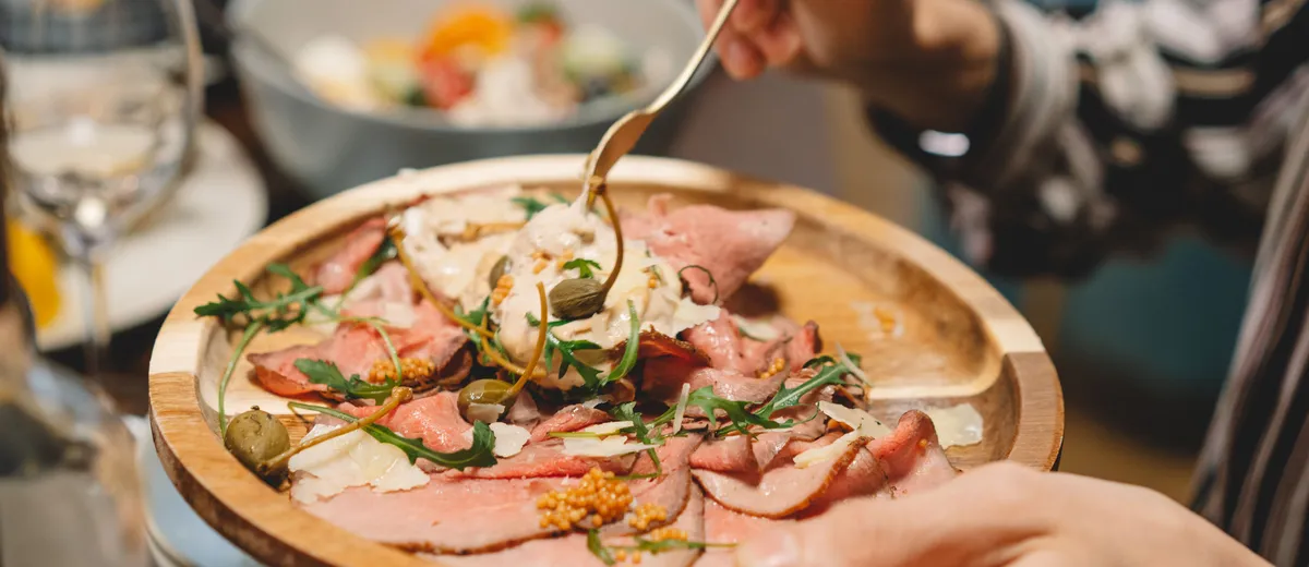 Fines tranches de veau froid dressées en assiette, nappées de sauce au thon crémeuse et décorées de câpres et de câprons